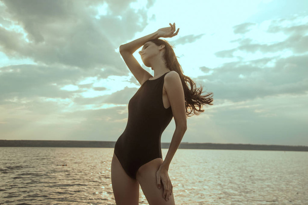 Stunning beautiful dark hair girl stripped in swimsuit on the sunset at the beach - 写真・画像
