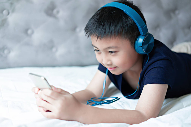 Pieni poika kuuntelee musiikkia sängyssä makuuhuoneessa rentoutua
 - Valokuva, kuva