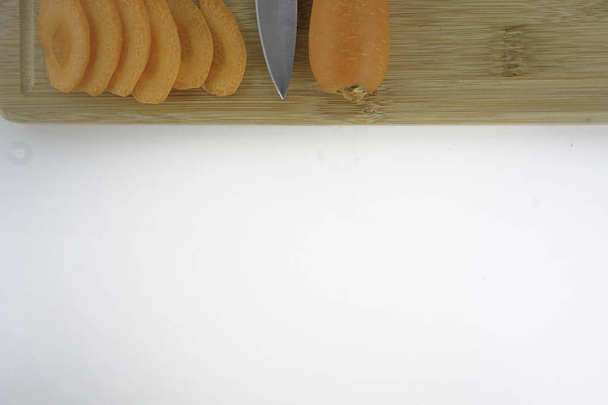 studio shot of carrot slices and knife with wooden board  - Foto, afbeelding