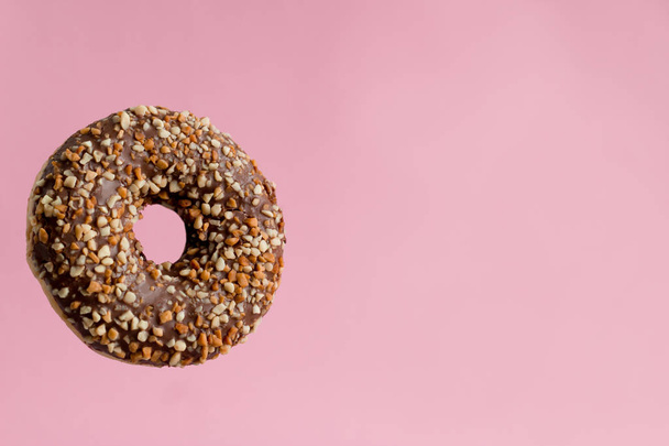 sweet chocolate  donut with nuts on pastel pink background copy space - Foto, immagini