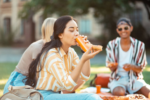 Chica alegre bebiendo en su picnic con amigos
. - Foto, imagen