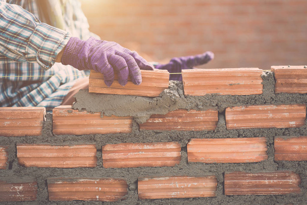 Worker installing bricks wall in process of house building - Foto, afbeelding