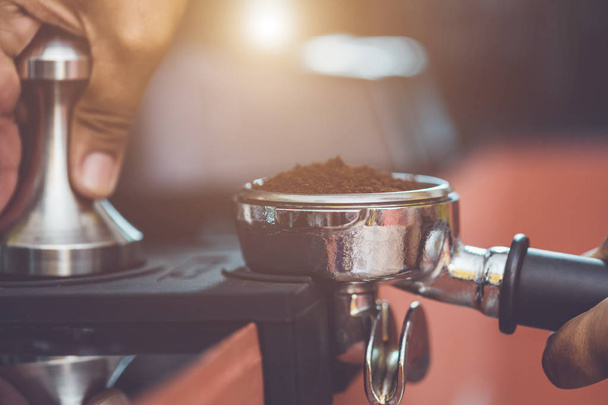 Hand of barista holding coffee tamper and making coffee preparat - 写真・画像