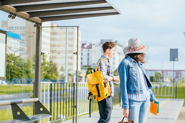 Gente estudiante viajando concepto. Pareja viajando juntos de pie en la estación de autobuses, esperando el transporte. Alta resolución
 - Foto, Imagen