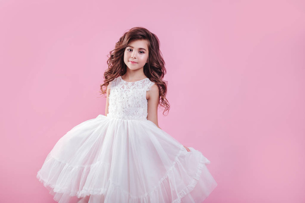 portrait of beautiful little girl in white dress on pink background - Фото, изображение