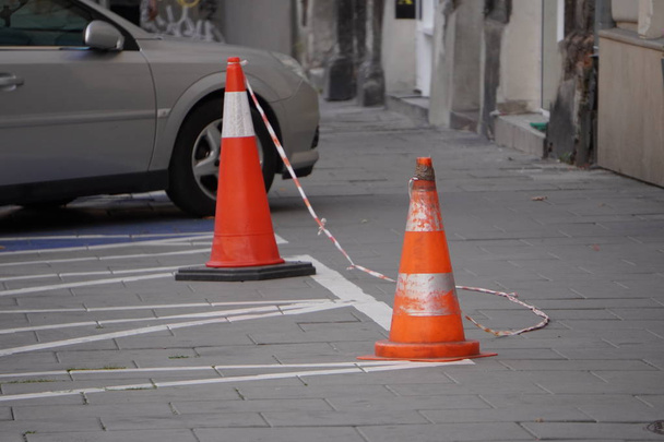 cones brancos alaranjados e fita esticada branca vermelha para restrições de trânsito e estacionamento. lugares de estacionamento proibidos
. - Foto, Imagem