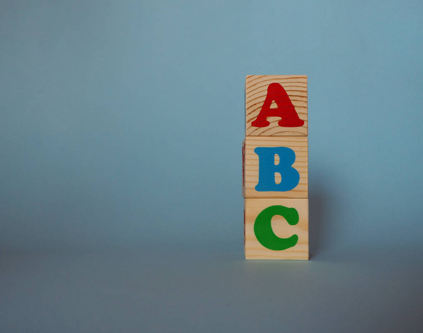 Alfabeto de madera bloques de juguete con el texto: abc. Niños aislados cubos ABC multicolores sobre fondo azul con espacio de copia. Regreso al concepto escolar
. - Foto, imagen