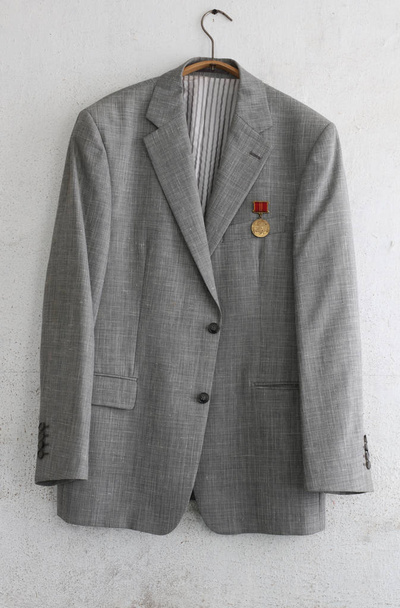 Stara kurtka z jednym radzieckim Medalem wisi na brudnej ścianie - Zdjęcie, obraz