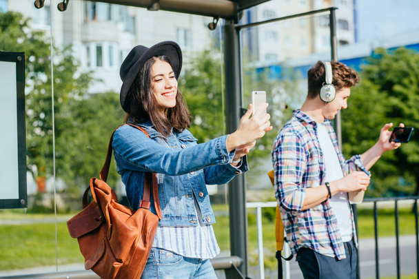 Feliz europeo viajero pareja bloggers hombre y mujer extraños tomando selfie con teléfonos inteligentes en parada de tranvía durante las vacaciones de verano viaje aventura
. - Foto, Imagen