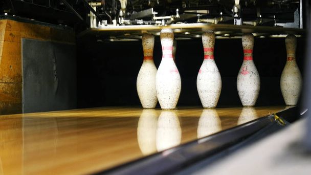 Vue des quilles debout à l'extrémité de l'allée de bowling et boule de bowling roulant sur la surface en bois dans un club de sport. Week-ends sportifs drôles dans un bowling
 - Photo, image