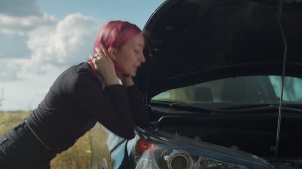 Confused hipster woman inspecting broken car engine - Materiał filmowy, wideo