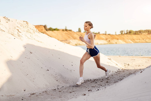 Beautiful young sexy athletic girl running on the nature summer morning - 写真・画像
