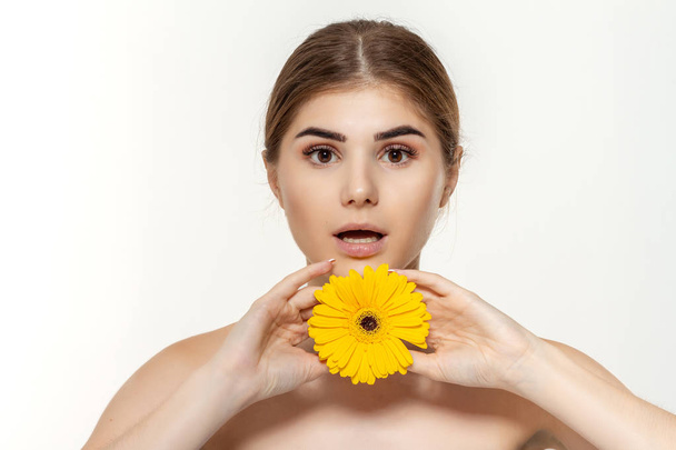 Portrét krásné mladé dívky se žlutou květinou, izolované na bílém pozadí. - Fotografie, Obrázek