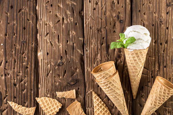 Top view white ice cream in waffle cone on rustic background. - 写真・画像