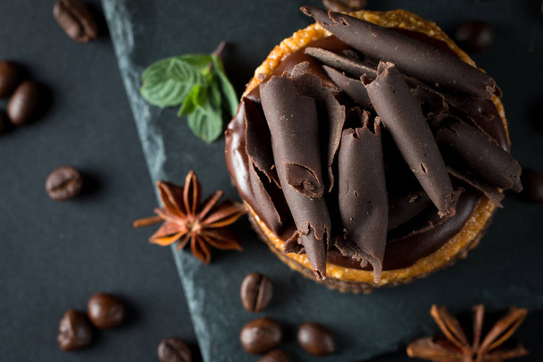 Chocolate cakes on black slatter board with mint, coffee beans on dark background, closeup photo. Fresh, tasty dessert food concept.  - Foto, afbeelding