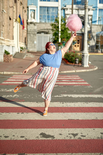 Fat and young woman with candy-floss on stick fly from crosswalk - Fotoğraf, Görsel