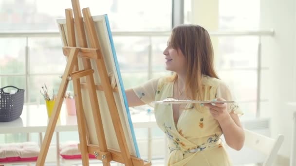 アート、創造性、趣味、仕事、クリエイティブな職業の概念。スタジオで絵画に取り組む女性アーティスト - 映像、動画