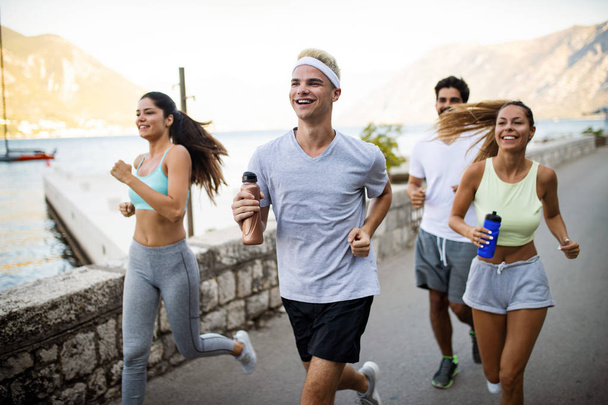 Τρέξιμο, Αθλητισμός, άσκηση και υγιεινό τρόπο ζωής έννοια. Ευτυχισμένοι άνθρωποι τζόκινγκ εξωτερική - Φωτογραφία, εικόνα