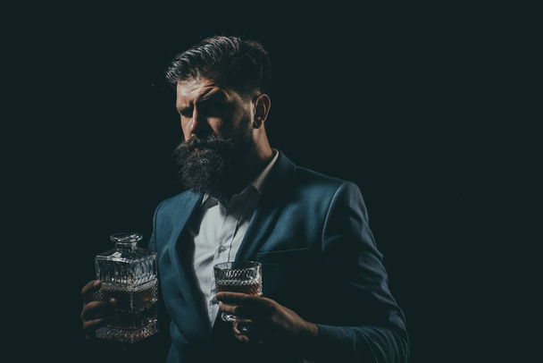 Attractive Bartender in whiskey bar. Stylish rich man holding a glass of old whisky. Man with beard holds glass brandy. - Фото, зображення