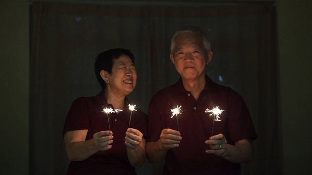 Asian senior couple playing sparklers, fire cracker at night. Co - Foto, Bild