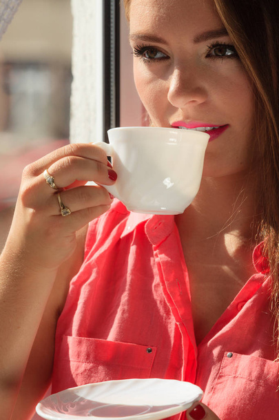 Woman looking through window, relaxing drinking coffee - Fotó, kép
