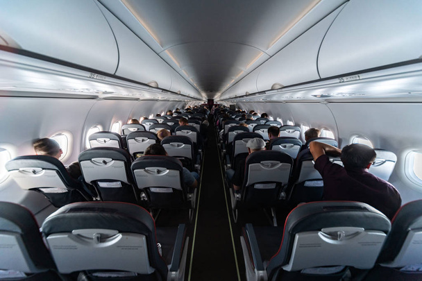 Vliegtuig cabine zitplaatsen met passagiers. Economy Class van de nieuwe goedkoopste goedkope luchtvaartmaatschappijen zonder vertraging of annulering van de vlucht. Reis naar een ander land. - Foto, afbeelding