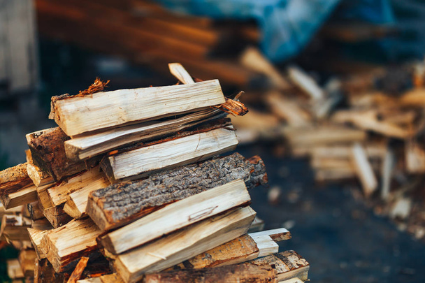 Un tas de bois empilé, préparé pour chauffer la maison. Cueillette de bois de chauffage pour l'hiver ou un feu de joie. L'homme tient du bois de feu dans ses mains
 - Photo, image