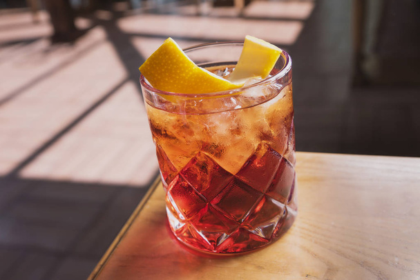 cocktail with soda, whiskey and orange zest on the background of a summer cafe on a wooden table - Photo, image