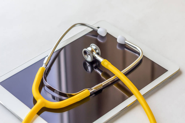 Tablet PC and stethoscope on a white background close up. - Zdjęcie, obraz
