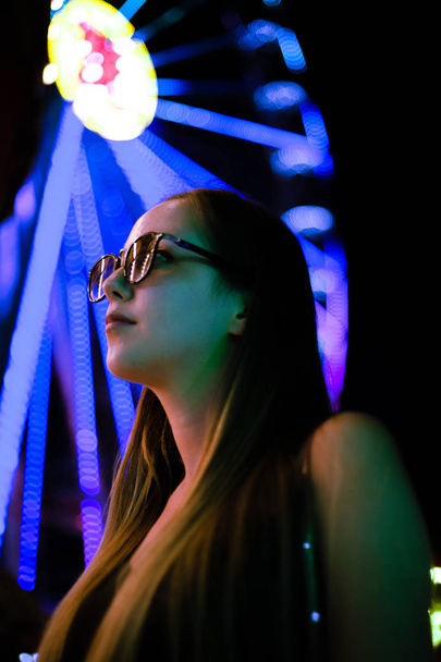 Hermosa chica en luces de neón por la noche en un parque de atracciones
. - Foto, imagen