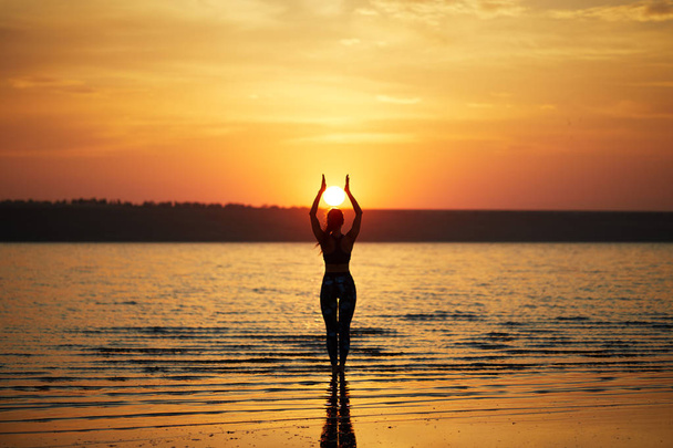 Yoga y fitness. Mujer joven practicando meditación matutina en la naturaleza en la playa
 - Foto, Imagen