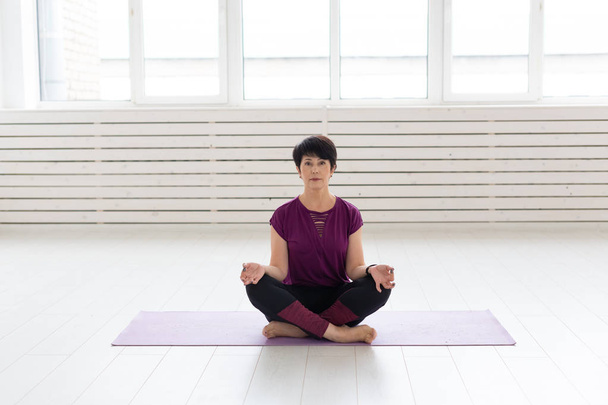Estilo de vida saudável, pessoas e conceito de esporte - Mulher de meia-idade atraente praticando ioga em pose de lótus
 - Foto, Imagem