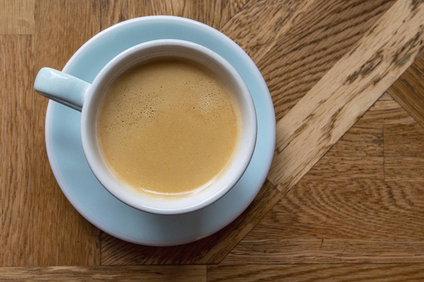 カフェの茶色の木製の空のテーブルに青いセラミックマグのコーヒーアメリカーノ - トップビュー - 写真・画像