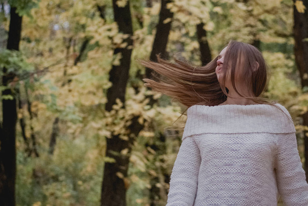 Zavřete portrét krásné dívky v bílém svetru blízko barevných podzimní listí. Kresba romantické ženy. Moc něžnosti jí zamávala vlasy - Fotografie, Obrázek