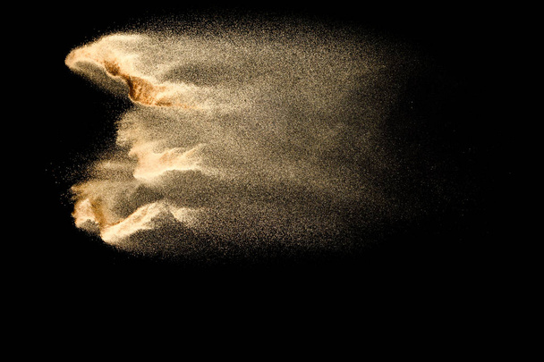 Abstract sand cloud.Golden colored sand splash agianst dark background.Yellow sand fly wave in the air. Sand explode on black background ,throwing freeze stop motion concept. - Photo, Image