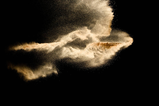 Αφηρημένο σύννεφο άμμου. Χρυσαφί χρώμα άμμου. Κίτρινη άμμος πετάει στον αέρα. Άμμος εκρήγνυται σε μαύρο φόντο, ρίχνοντας την έννοια της κίνησης πάγωμα στάση. - Φωτογραφία, εικόνα