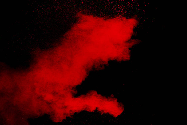Czerwony kolor wybuch proszku na czarnym tle.Freeze ruchu cząstek czerwonego pyłu rozpryskiwania. - Zdjęcie, obraz