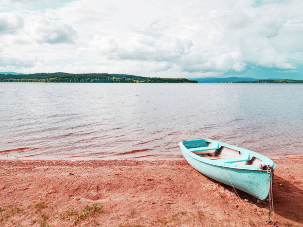 Barco de pesca azul ancorado na areia da praia do lago. Nível suave
 - Foto, Imagem