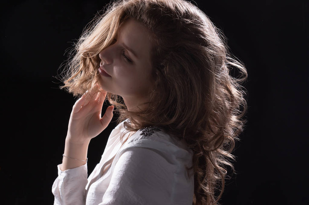 psychological portrait of a young hair model with long curly hair on a dark background - Photo, Image