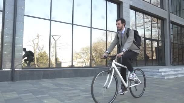 Modern young businessman bicycle rider in suit and with backpack outdoors - Video