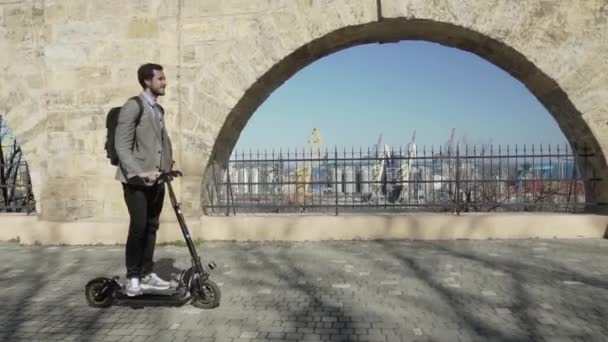 Young business man in suit, tie and backpack riding on electric scooter,modern office worker ride on scooter outdoors - Materiał filmowy, wideo