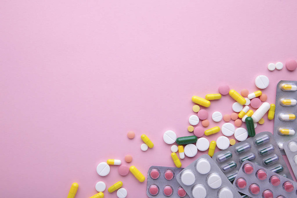 Colored pills and tablets in blister on a pink background, top view - Foto, imagen