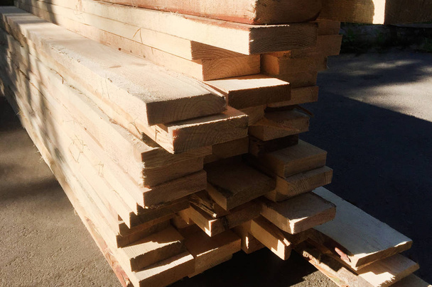 Des planches de bois sciées reposent sur le sol près de la maison. Matériau de construction et de réparation. Gros plan
. - Photo, image