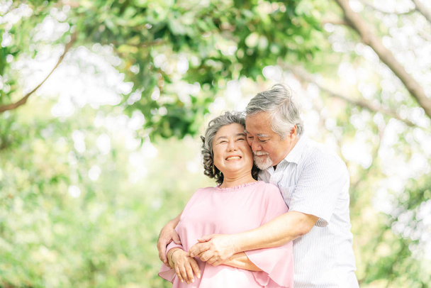 Ευτυχισμένο ζευγάρι ηλικιωμένων στην αγάπη αγκαλιάζοντας στο πάρκο - Φωτογραφία, εικόνα