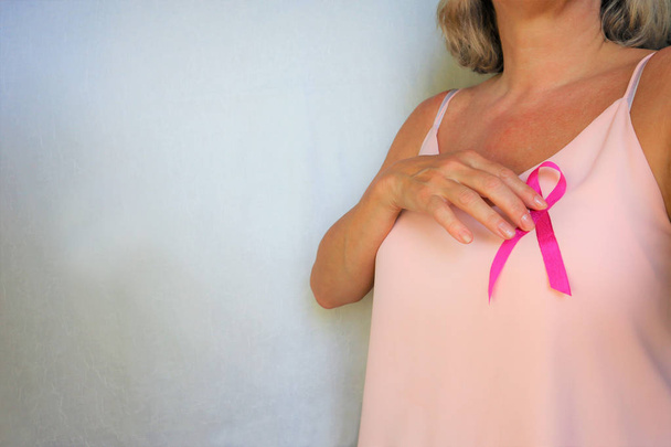 Γυναίκα με ροζ κορδέλα στο στήθος. ώριμο θηλυκό δείχνοντας σύμβολο r - Φωτογραφία, εικόνα