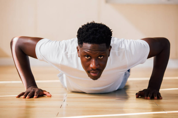 Portrait of young African American man doing push-up on the floor - Фото, зображення