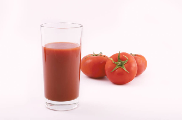 Tomato juice in a glass and ripe tomatoes on a white background - Foto, Imagem