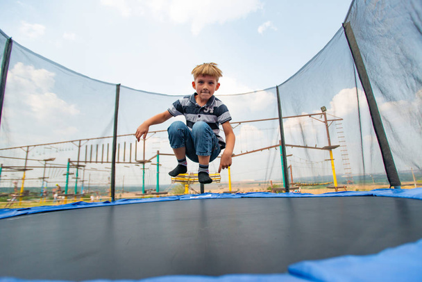 O menino pula em um trampolim em um parque de diversões, realizando várias acrobacias
. - Foto, Imagem