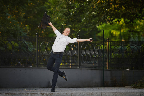 クレイジー若いビジネスマンはバッグで通りで踊ります。勝利を祝うビジネスにおける柔軟性と優れた優雅さ - 写真・画像