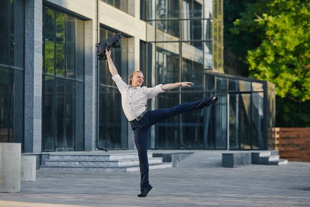 Giovane uomo d'affari pazzo che balla per strada con la borsa. Festeggiamo la vittoria. Flessibilità e grazia nelle imprese
 - Foto, immagini